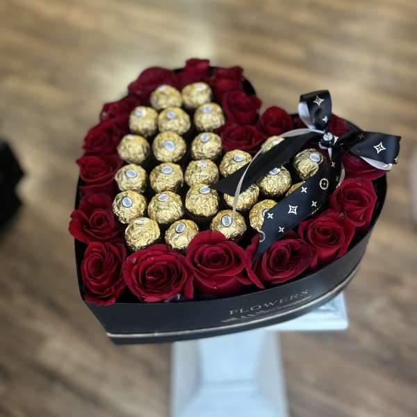 Heart-shaped rose box filled with chocolates and a black ribbon