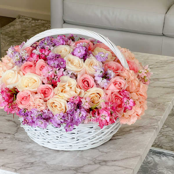 Basket of pink, cream, and purple flowers on a table