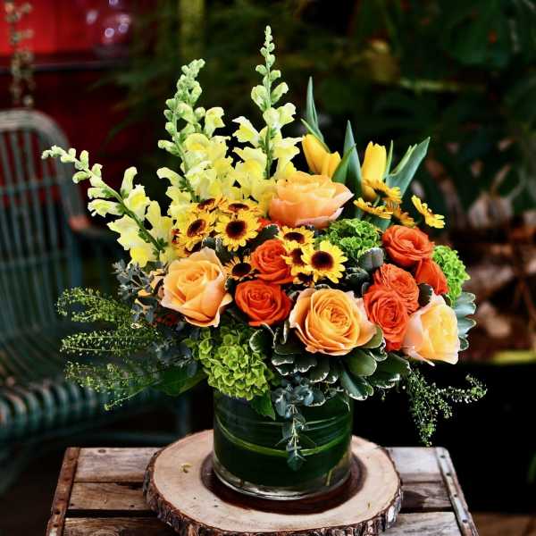 Orange roses and yellow snapdragons in a glass vase