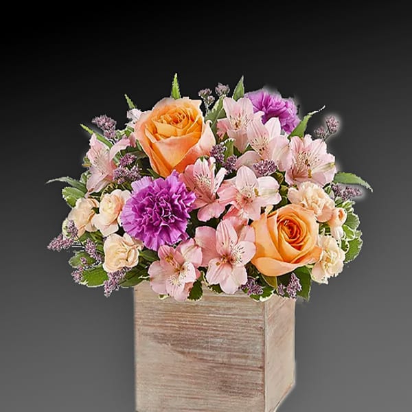 Bouquet of peach roses and pink flowers in a wooden box