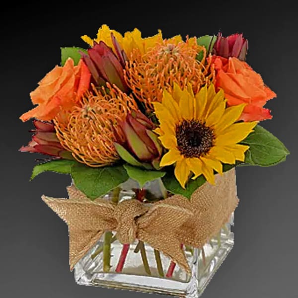 Bright mixed bouquet with a sunflower in a glass vase