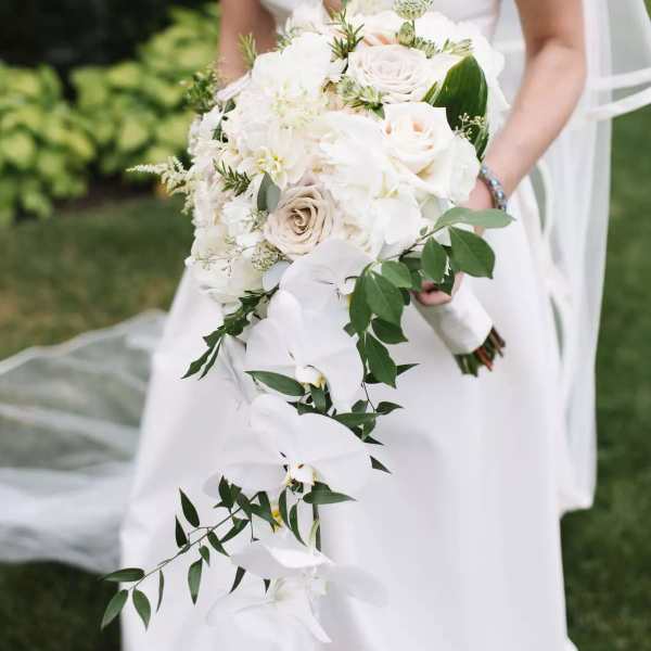 Bride holding a white bouquet with cascading orchids and roses