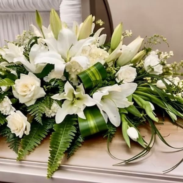 White lilies and roses arranged in a low casket spray