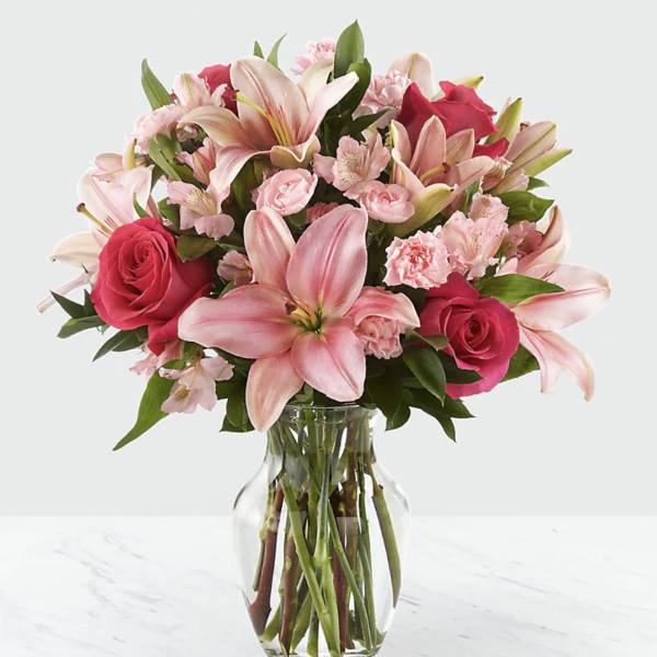 Pink lilies, roses, and carnations in a clear glass vase