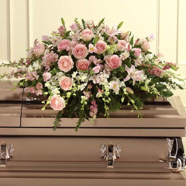 Pink rose and lily casket spray on a beige casket
