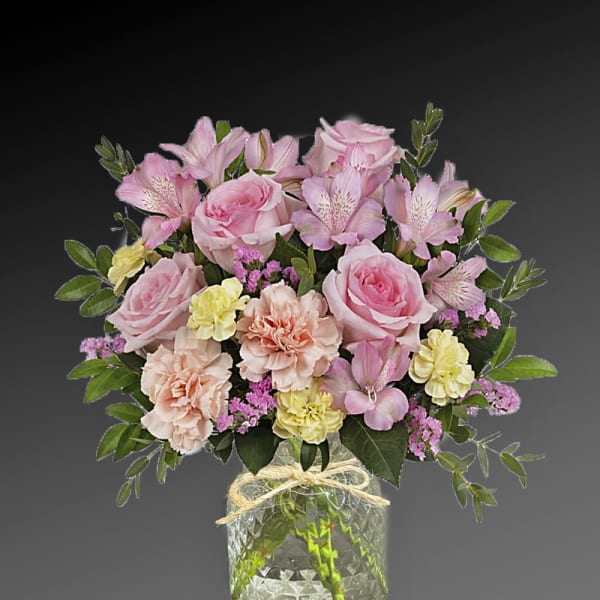 Pink roses and mixed pastel flowers in a clear glass vase