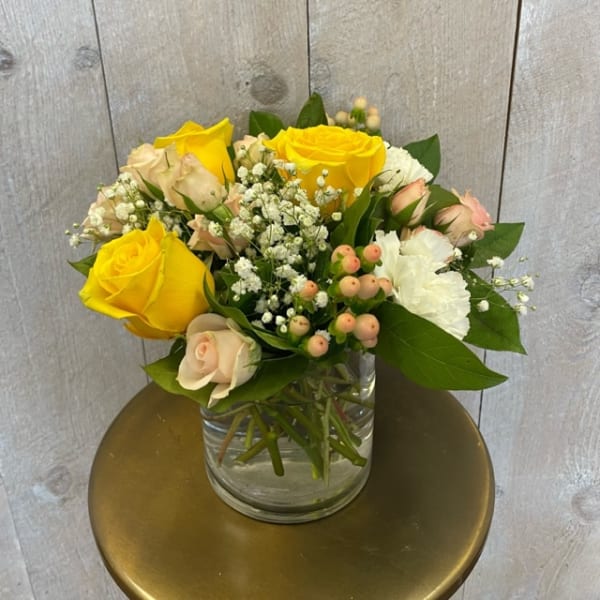 Yellow and blush roses arranged in a clear glass vase