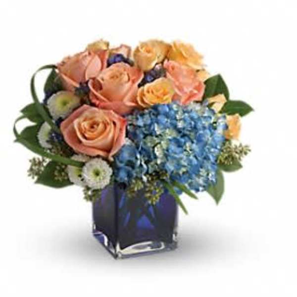 Peach roses and blue hydrangeas in a blue glass vase