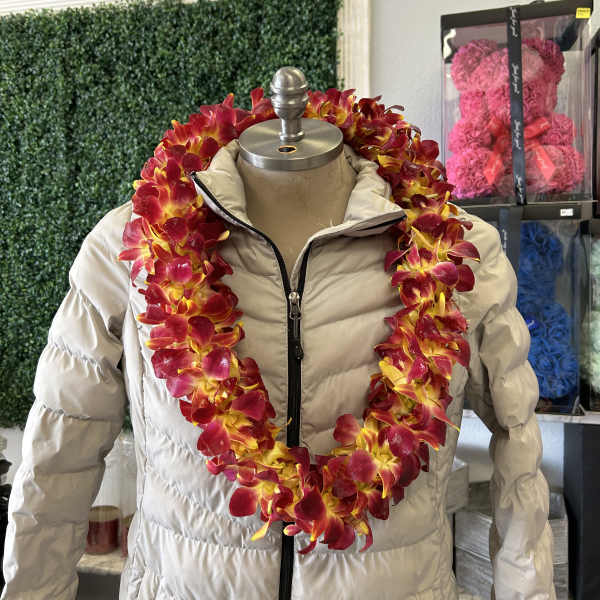 Red and yellow orchid lei draped over a beige puffer jacket on a mannequin.