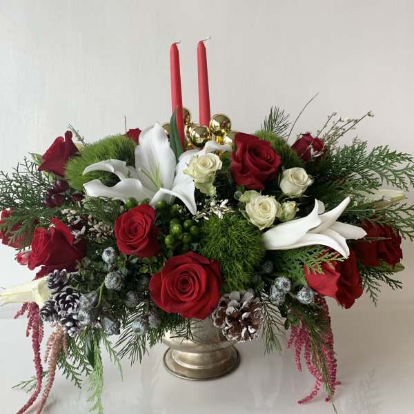 Red roses and white lilies arranged in a gold vase with two red candles