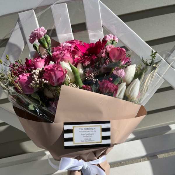 Pink and white mixed bouquet wrapped in blush paper with a white ribbon