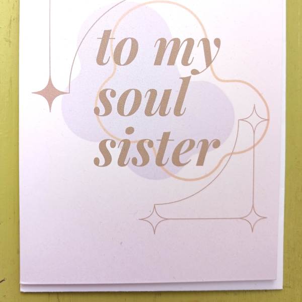 Greeting card reading 'to my soul sister' in tan script with pastel shapes and star accents.