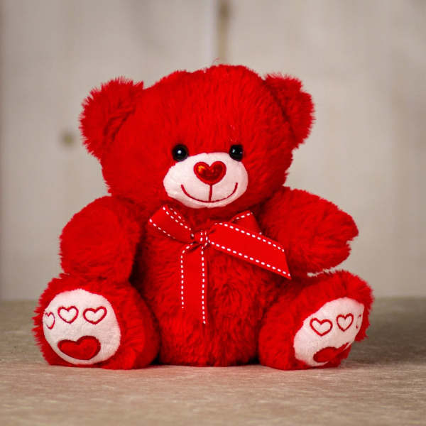 Red teddy bear with a heart nose and ribbon bow