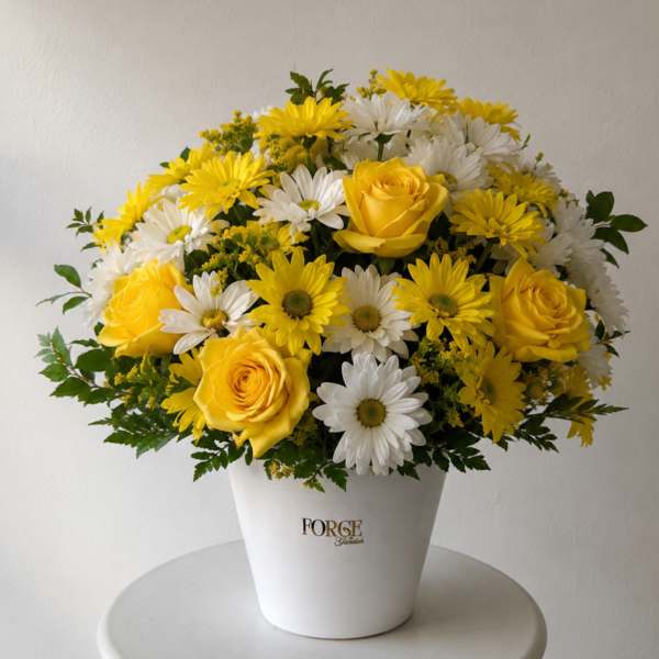 Yellow roses and white daisies arranged in a white vase