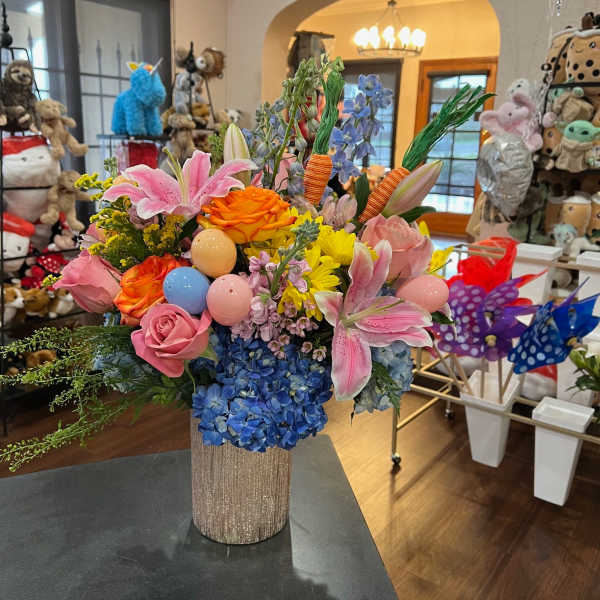 Colorful bouquet with lilies, roses, hydrangeas, and decorative eggs in a glittery vase