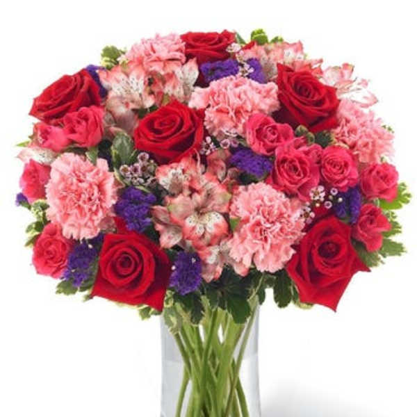 Bouquet of red roses and pink carnations in a clear glass vase