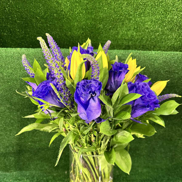 Purple roses and yellow tulips in a clear glass vase