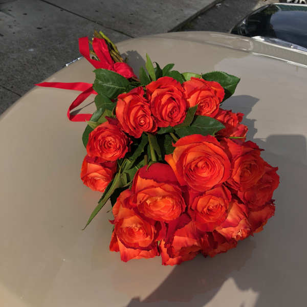 Bouquet of orange-red roses tied with a red ribbon