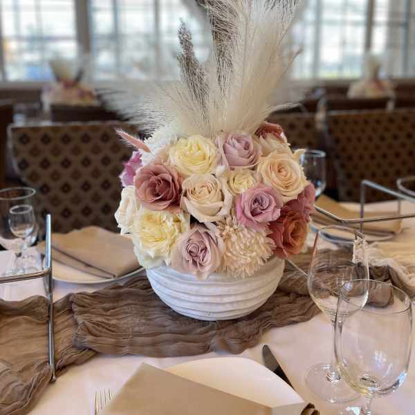 Pastel rose centerpiece in a white bowl vase with tall white plumes