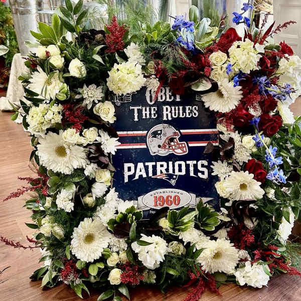Patriots-themed floral wreath with white, red, and blue flowers around a sign
