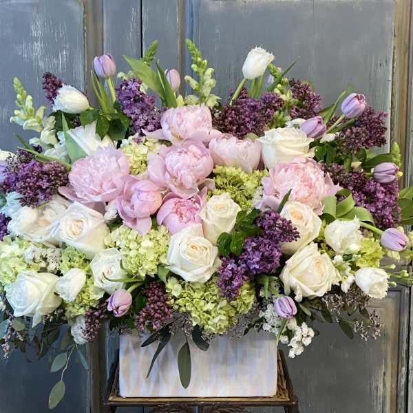 Large pastel floral arrangement with pink and white roses in a white container