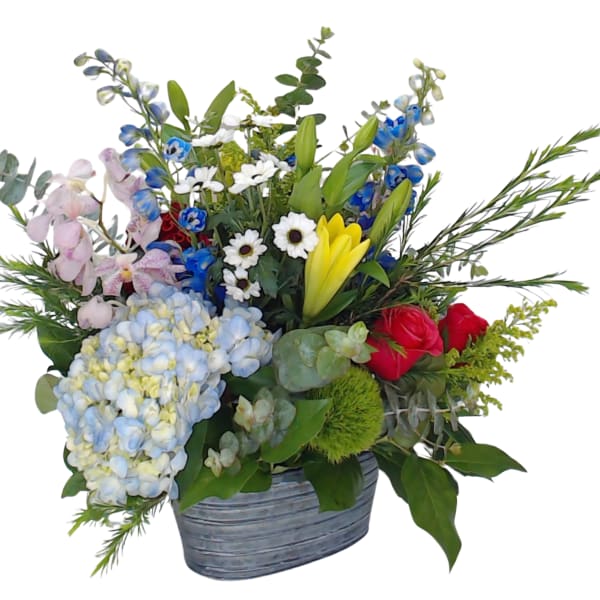 Mixed flower arrangement in a gray container with blue, pink, yellow, and red blooms