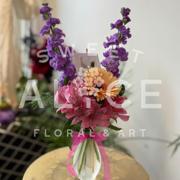 Bouquet of purple, pink, and orange flowers in a ribbed glass vase
