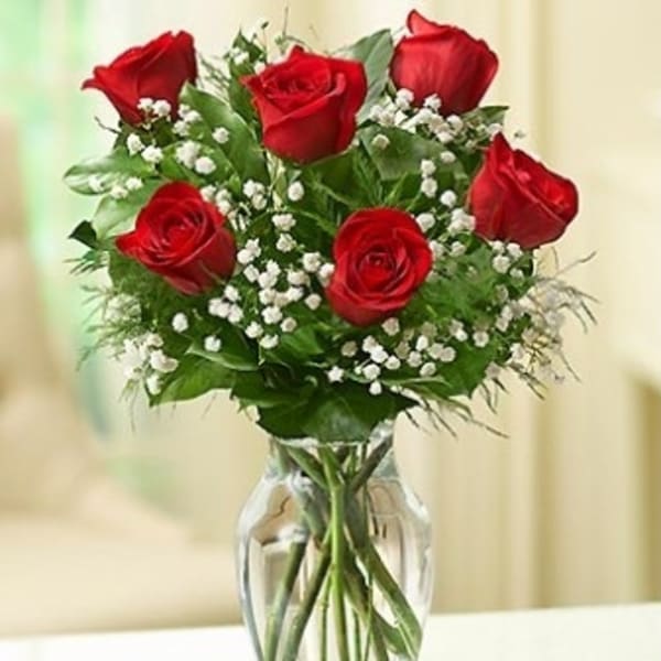 Red roses with baby's breath in a clear glass vase