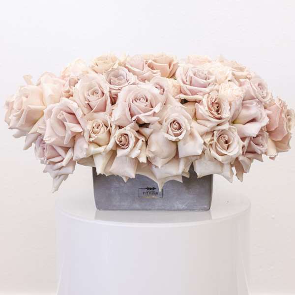 Pale pink rose arrangement in a gray rectangular vase