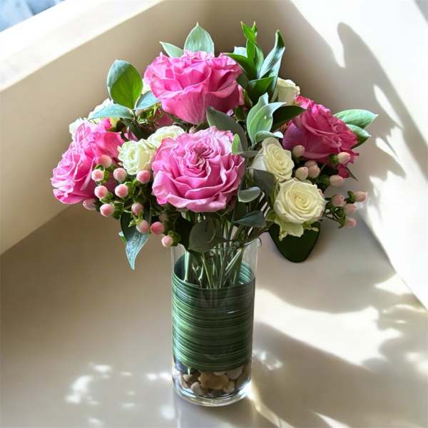 Pink and white roses arranged in a clear glass vase