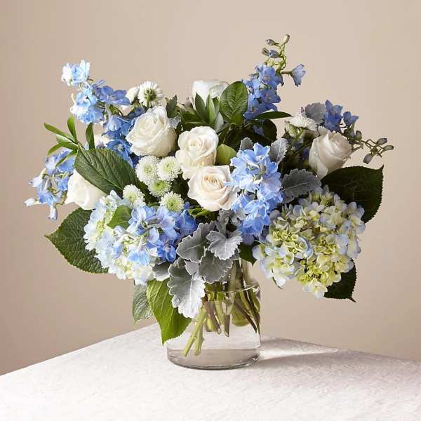 Blue and white bouquet of roses and hydrangeas in a glass vase