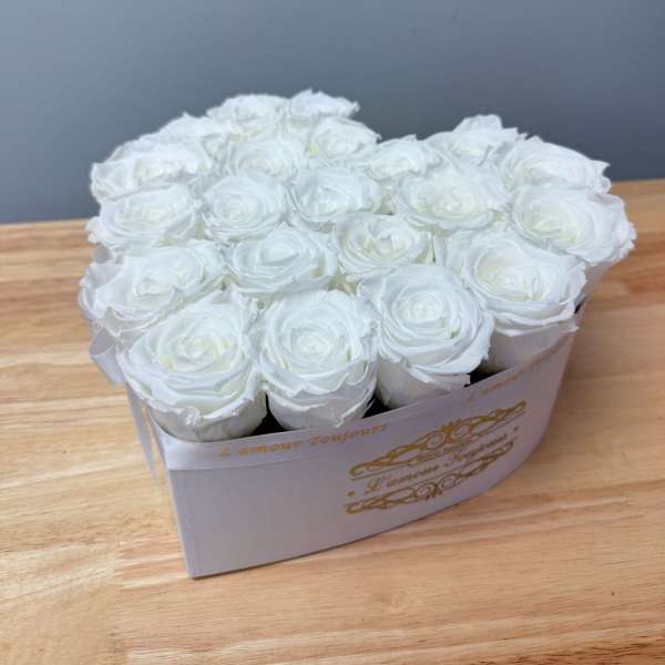 White roses arranged in a rectangular box on a wooden table