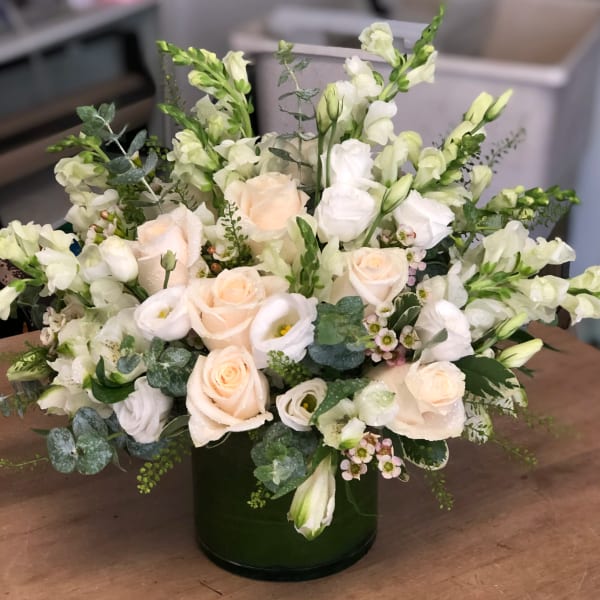 Cream roses and white blooms arranged in a dark green vase