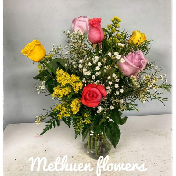 Mixed roses and small filler flowers arranged in a clear glass vase