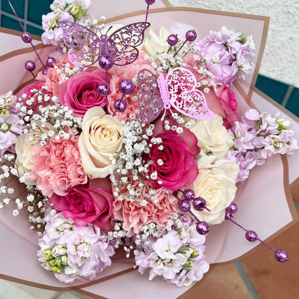Pink and cream rose bouquet with lilac flowers and butterfly picks