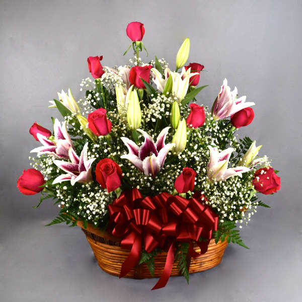 Basket arrangement of red roses and white lilies with a red ribbon