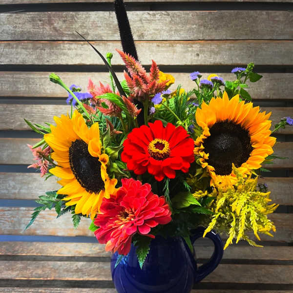Bright mixed bouquet with sunflowers and zinnias in a blue mug