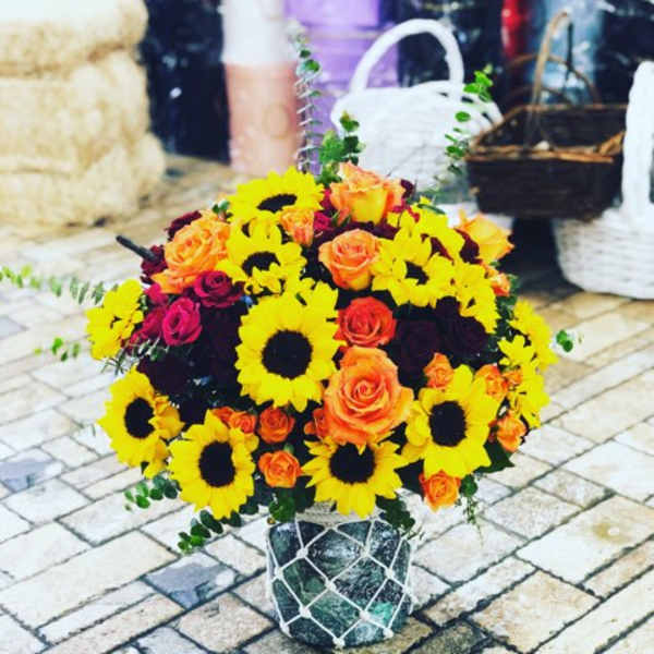 Bouquet of sunflowers and orange roses in a decorative container