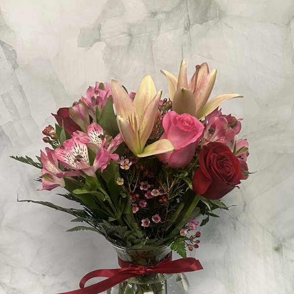 Bouquet of pink lilies, roses, and alstroemeria in a glass vase