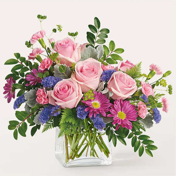 Pink roses and purple daisies in a clear glass vase
