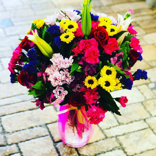 Colorful mixed bouquet in a pink vase with roses and lilies