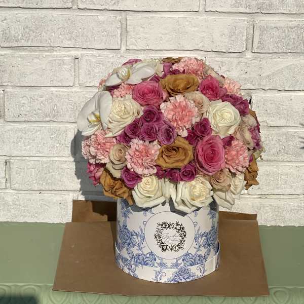 Round bouquet of pink, white, and peach flowers in a decorative box