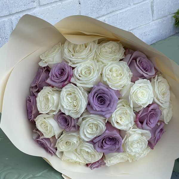 Bouquet of white and lavender roses wrapped in cream paper