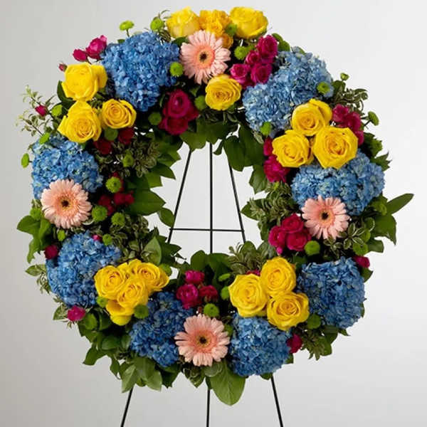 Colorful floral wreath with blue hydrangeas, yellow roses, and pink gerbera daisies