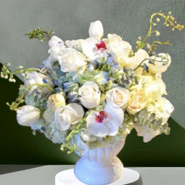 White roses and orchids arranged in a white vase