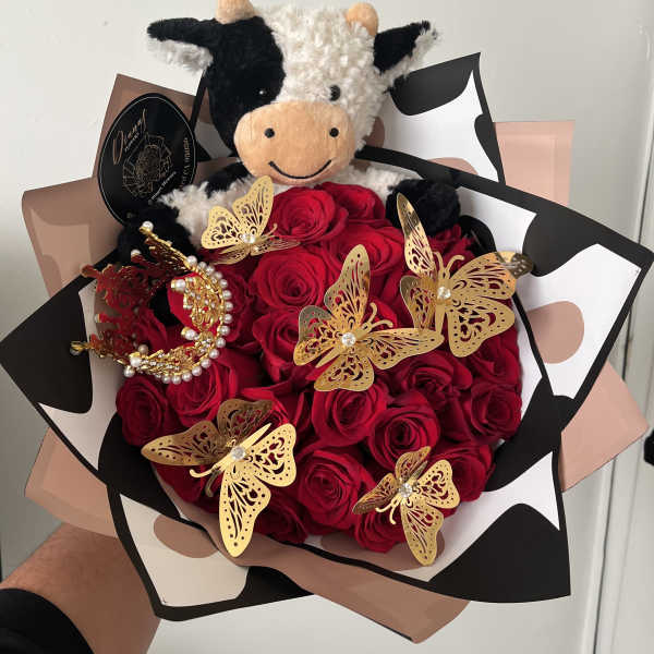 Bouquet of red roses with a plush cow and gold butterfly decorations