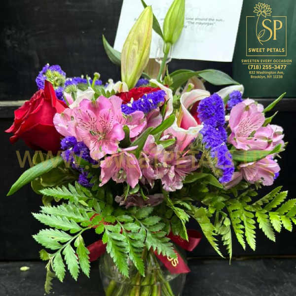 Mixed bouquet of roses, lilies, and pink alstroemeria in a glass vase