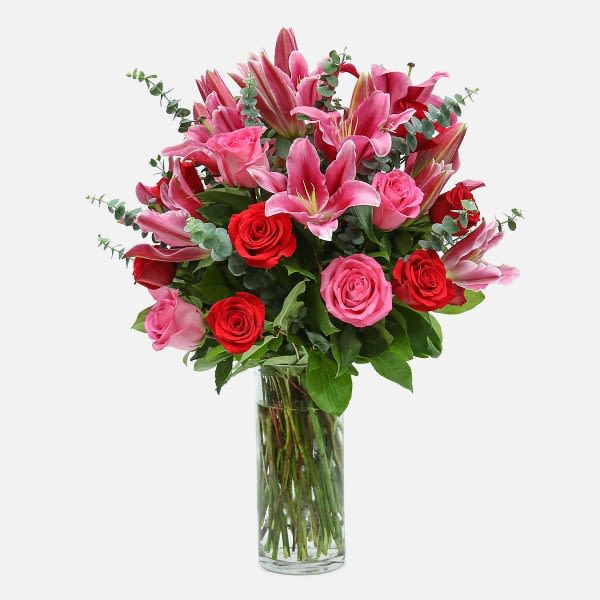 Bouquet of pink lilies and red roses in a clear glass vase