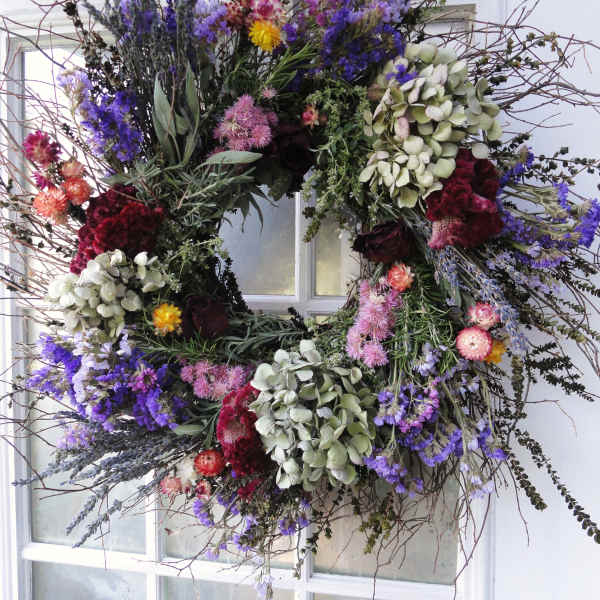 Large floral wreath with purple, pink, and white blooms on a window