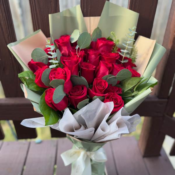 Bouquet of red roses wrapped in pale green and white paper